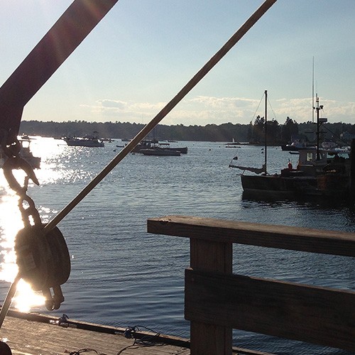 A view of the harbor in Boothbay Harbor, Maine with lobster boats and pilings in view.