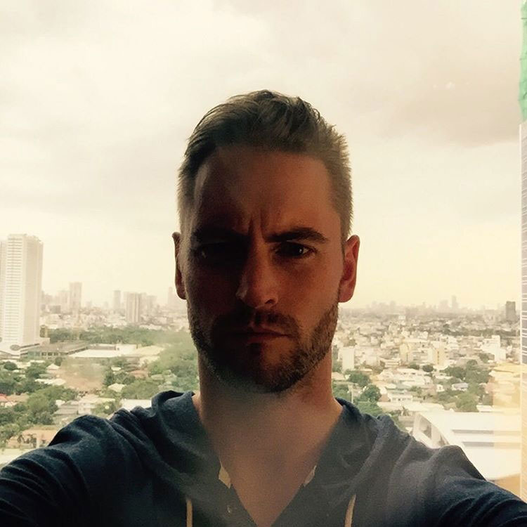 Kevin Batdorf, web developer for SlickFish Studios seen in front of a window with downtown Bangkok, Thailand behind him.